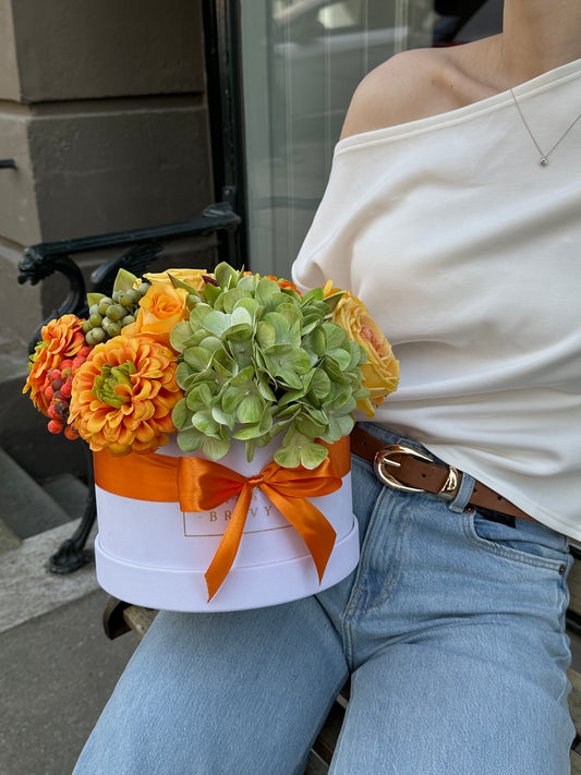Solé blomsteræske med røde, orange og champagnefarvede blomster